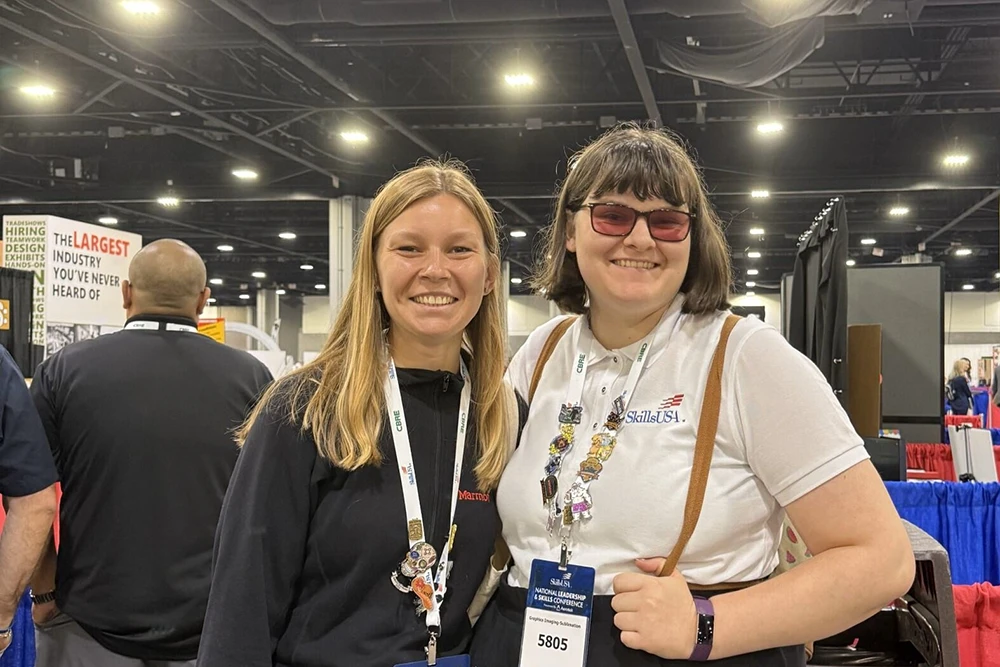 Two women smile and pose for photo together.
