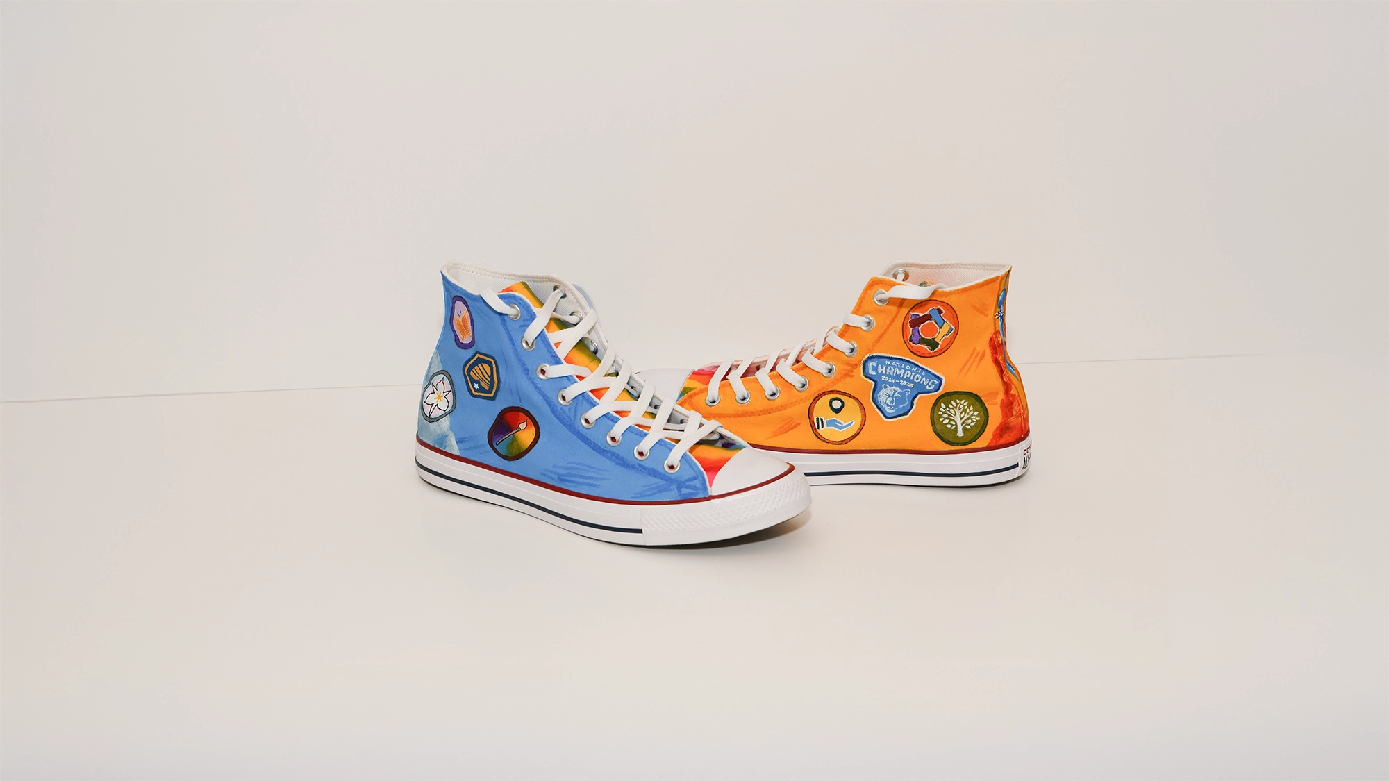 A pair of shoes, one blue and one orange, with white laces and rainbow-striped tongues. 