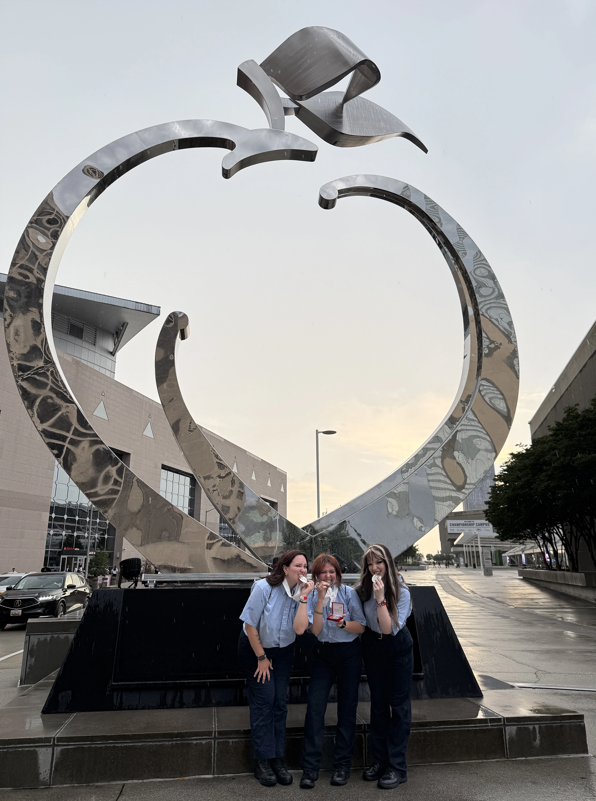 LCC Forensic Science Students, left to right, Kylee Hermeling, Kennedi Leon, and Haylee Ramirez celebrate in front of a sculpture outside the National Skills USA competition in Atlanta, Georgia.