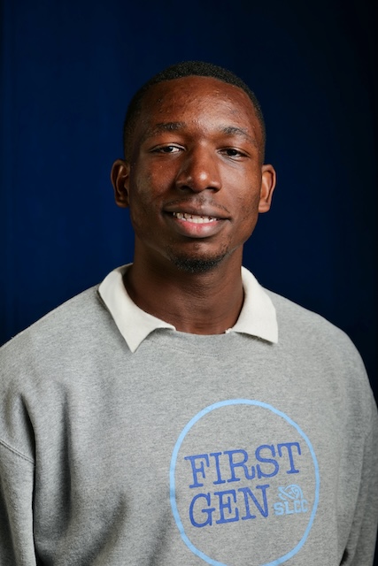 Person wearing a gray sweatshirt with the text 'FIRST GEN' and 'SLCC' inside a blue circle, standing against a dark blue background. 