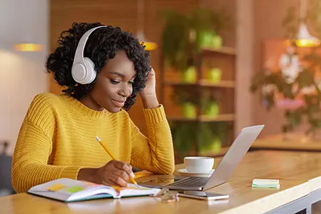 a woman with headphones doing homework on her laptop